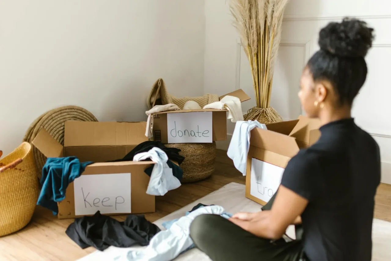 A Woman Sitting in front of Cardboard Boxes in a messy room
